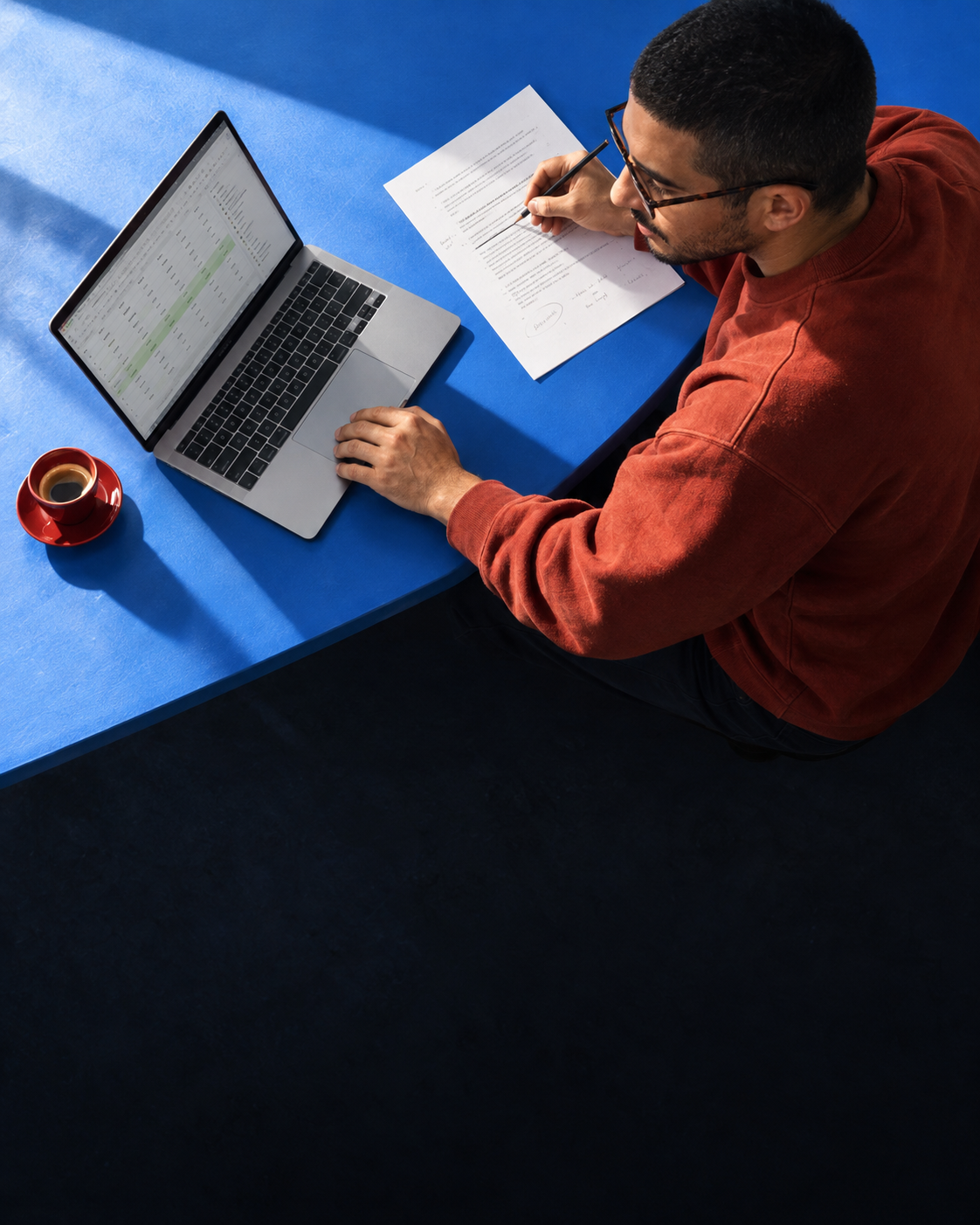 A person reviewing campaign notes and laptop data at a blue table.