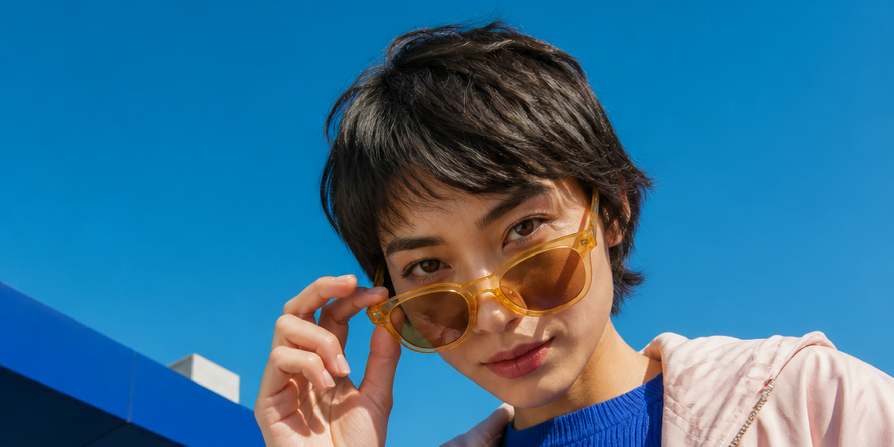 Marketing professional holding a phone against a vivid blue architectural background.